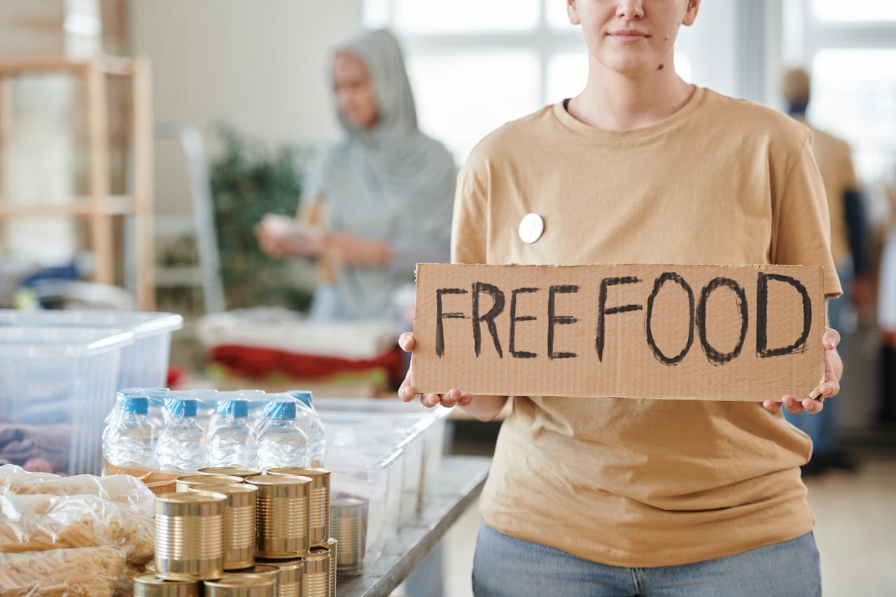 Volunteer holding a free food sign at a donation center, promoting charity and aid.